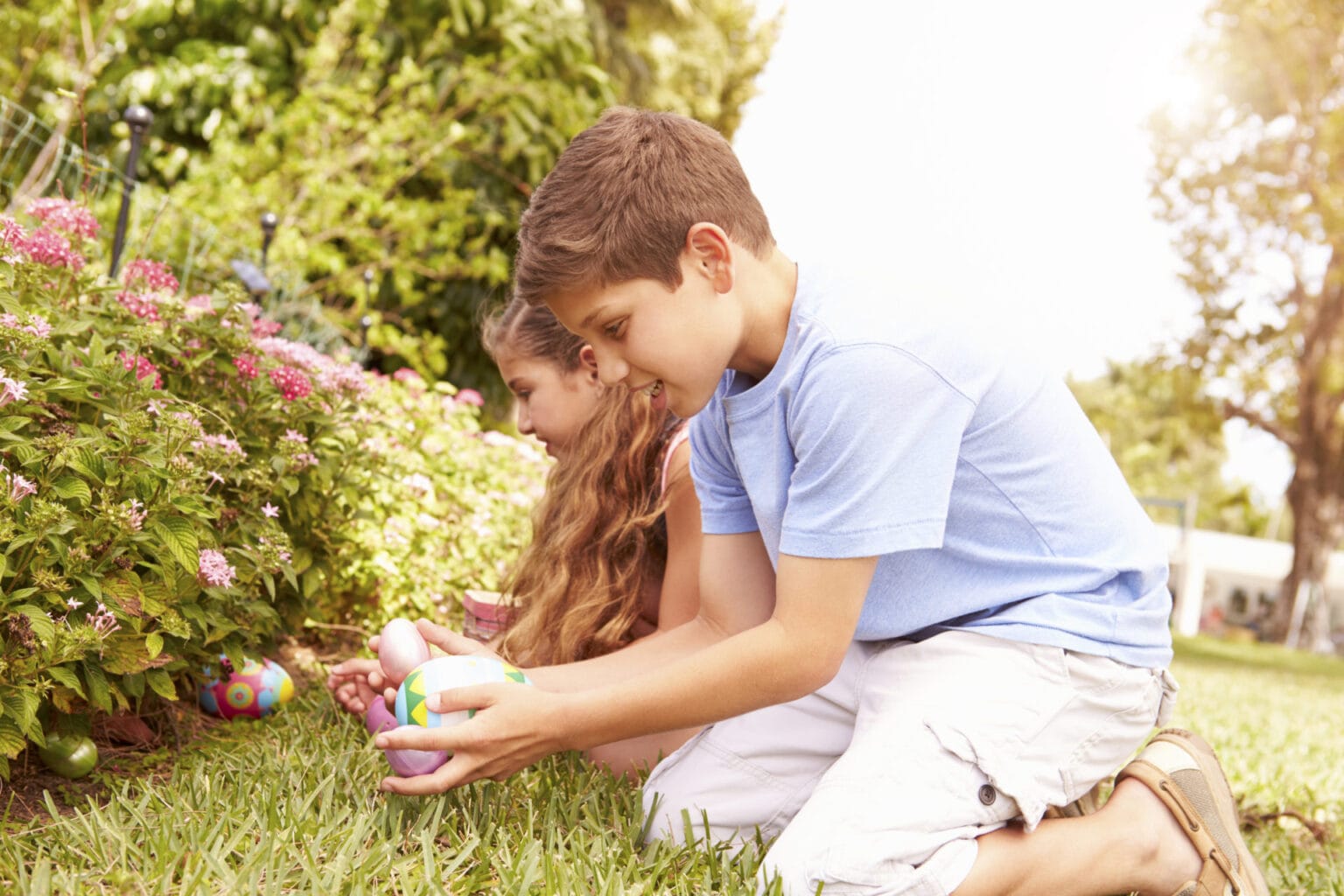 two children having easter egg hunt in garden P724MCW